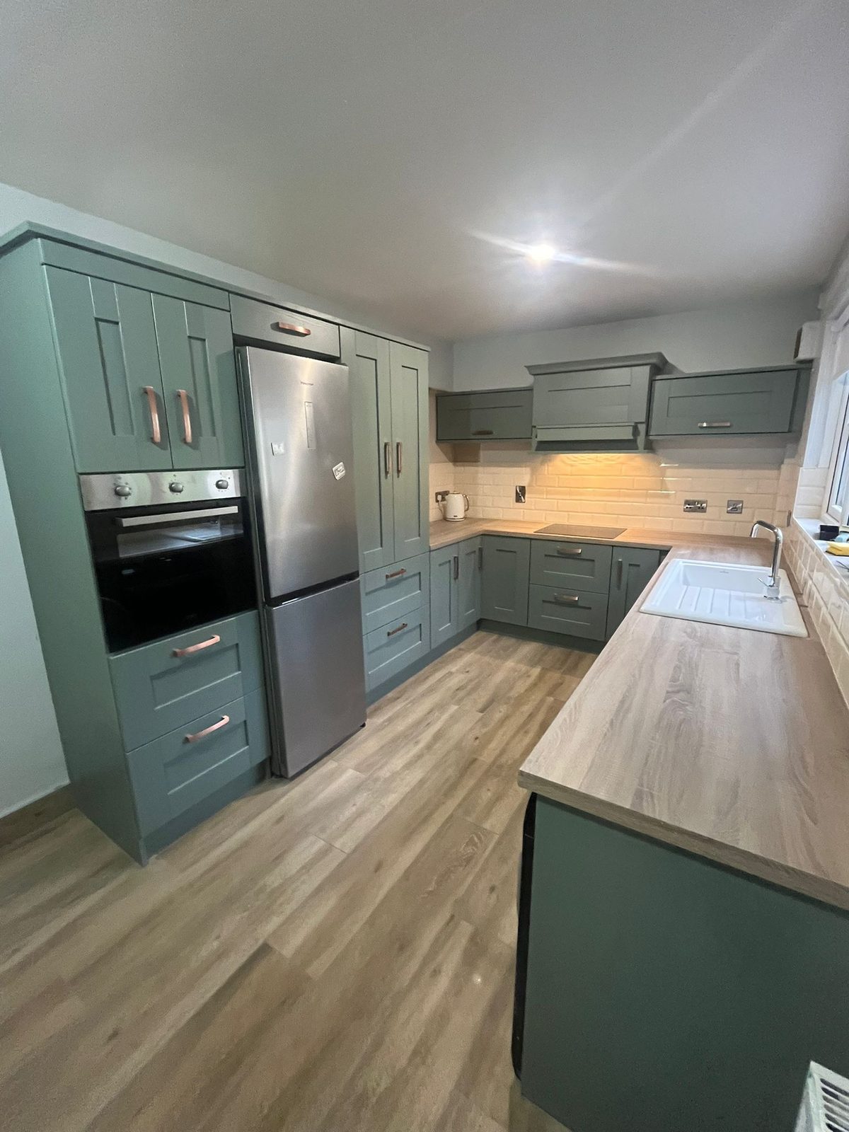 Sage-green shaker kitchen with brushed copper handles