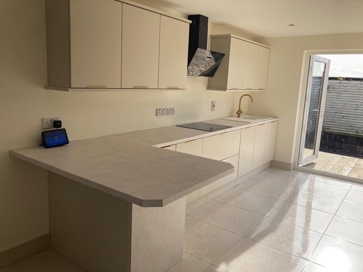 Handleless kitchen with concrete-effect worktop and garden doors