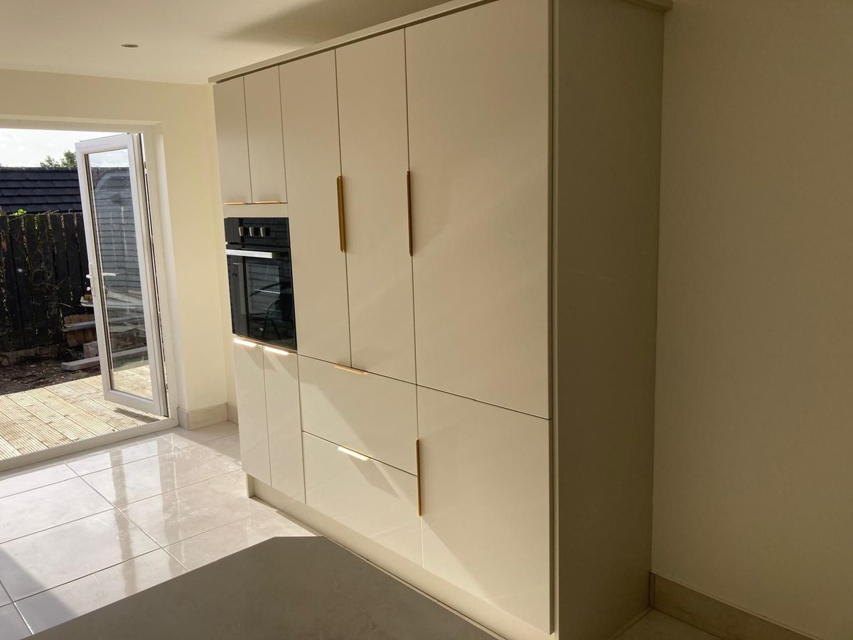 Gloss cream handleless kitchen with brass detailing